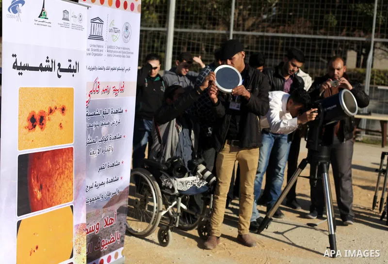 A Palestinian student looks through a telescope at the sun during a practical astronomer training to identify the Sunspot color and its impact, in Gaza City on February 13, 2014. Photo by Ashraf Amra
