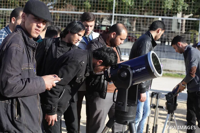 A Palestinian student looks through a telescope at the sun during a practical astronomer training to identify the Sunspot color and its impact, in Gaza City on February 13, 2014. Photo by Ashraf Amra