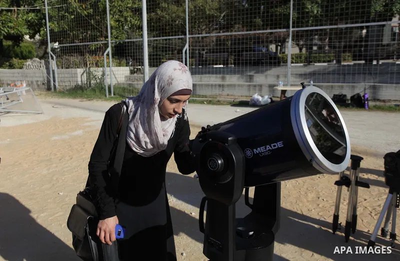 A Palestinian student looks through a telescope at the sun during a practical astronomer training to identify the Sunspot color and its impact, in Gaza City on February 13, 2014. Photo by Ashraf Amra