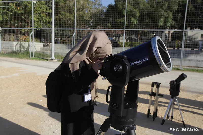 A Palestinian student looks through a telescope at the sun during a practical astronomer training to identify the Sunspot color and its impact, in Gaza City on February 13, 2014. Photo by Ashraf Amra