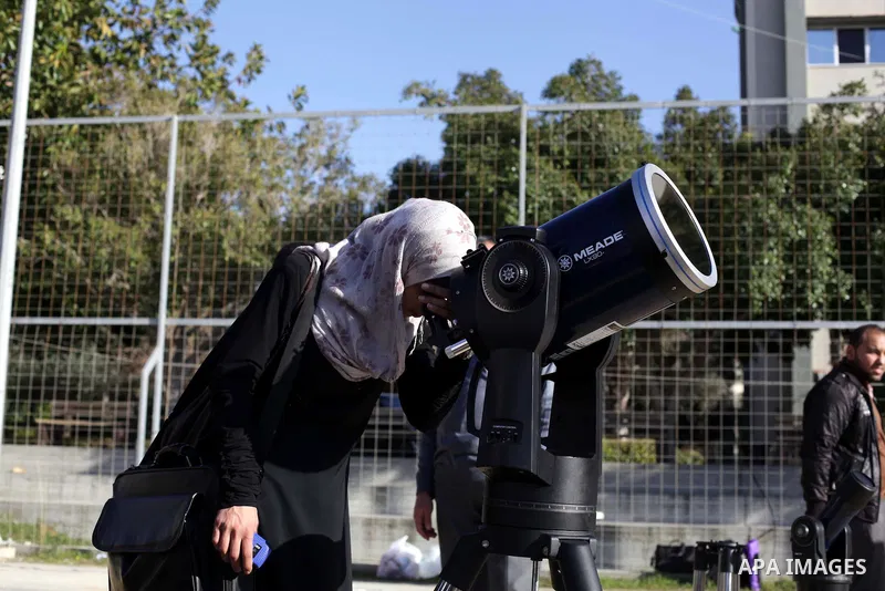 A Palestinian student looks through a telescope at the sun during a practical astronomer training to identify the Sunspot color and its impact, in Gaza City on February 13, 2014. Photo by Ashraf Amra