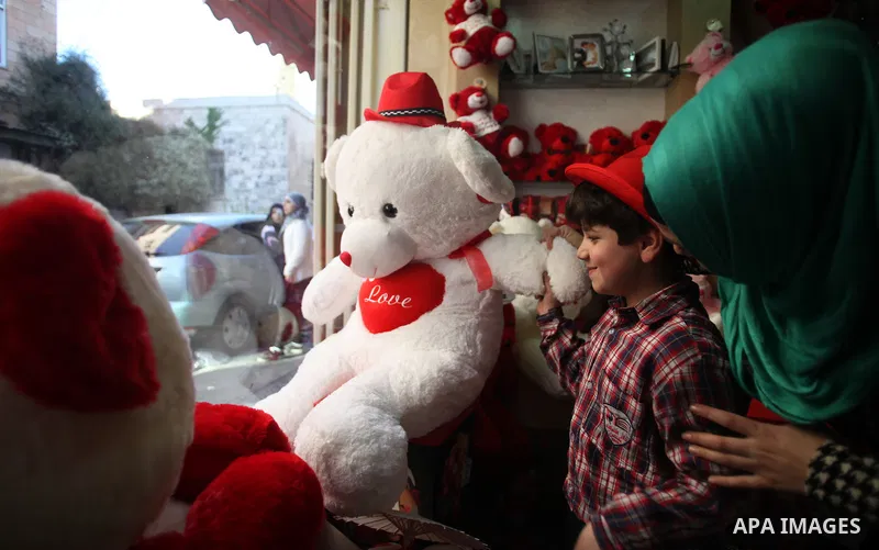 A Palestinian boy with his mother shop in a gift store ahead of Valentine's day in Jerusalem on February 13, 2014. Valentine's Day is increasingly popular among younger Palestinians, many of whom have taken up the custom...