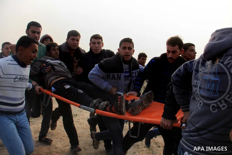 Palestinians carry a fellow protester wounded during clashes with Israeli forces near the border with Israel, east of Jabalia refugee camp in northern Gaza Strip on February 14, 2014. The Israeli army fired live rounds a...