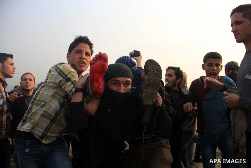 Palestinians carry a fellow protester wounded during clashes with Israeli forces near the border with Israel, east of Jabalia refugee camp in northern Gaza Strip on February 14, 2014. The Israeli army fired live rounds a...