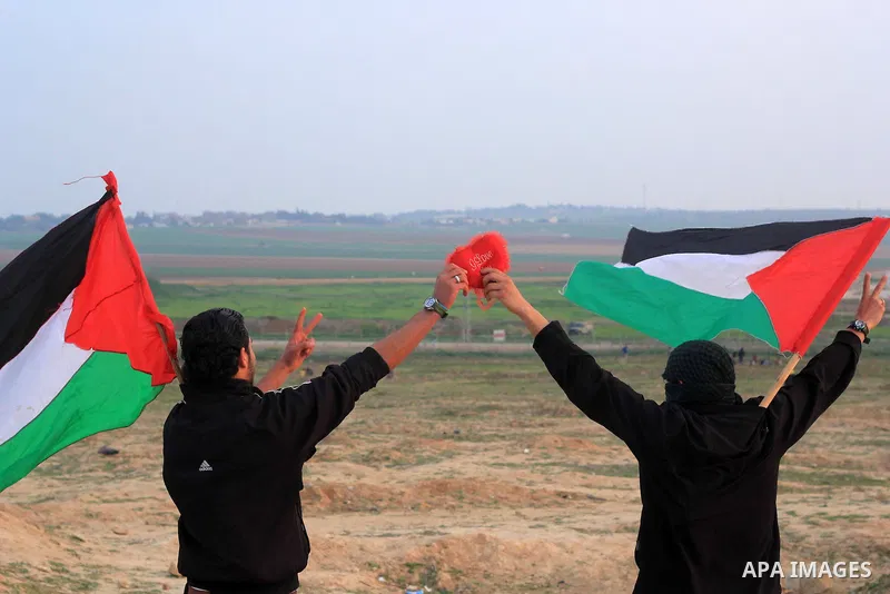 Palestinian protesters hold national flags and red hearts during clashes with Israeli forces near the border with Israel, east of Jabalia refugee camp in northern Gaza Strip on February 14, 2014. The Israeli army fired l...