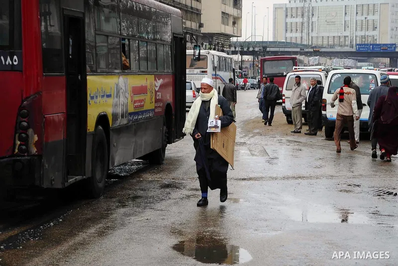Egyptians walk in a street during a heavy rain in Cairo, Egypt, Saturday, Feb. 15, 2014. An unusual outbreak of rain poured down on Cairo on Saturday, flooding some streets to worsen the Egyptian capital's already infamo...