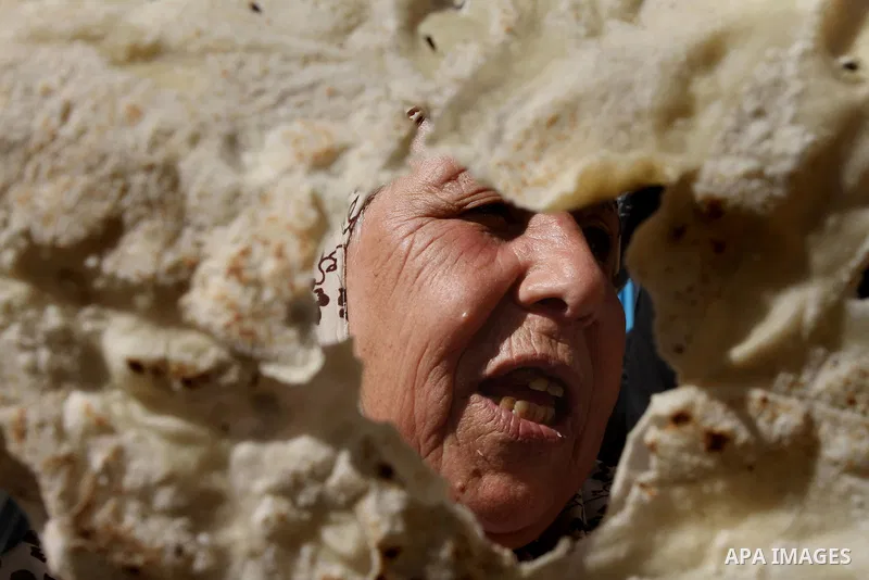 A Palestinian woman holds a bread during a protest against the UNRWA decision to reduce of the food aid in front of the headquarters United Nations Relief and Works Agency (UNRWA), in Gaza city, on Feb. 18, 2014. Photo b...