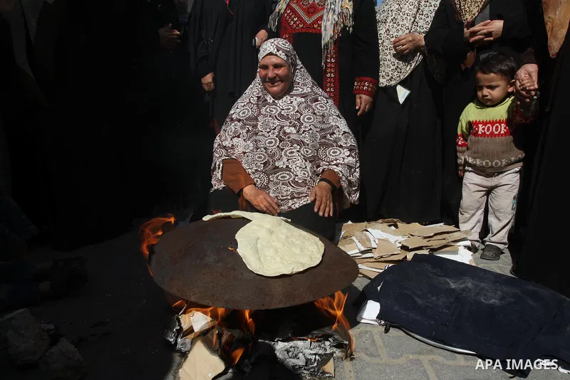 A Palestinian woman bakes bread during a protest against the UNRWA decision to reduce of the food aid in front of the headquarters United Nations Relief and Works Agency (UNRWA), in Gaza city, on Feb. 18, 2014. Photo by...