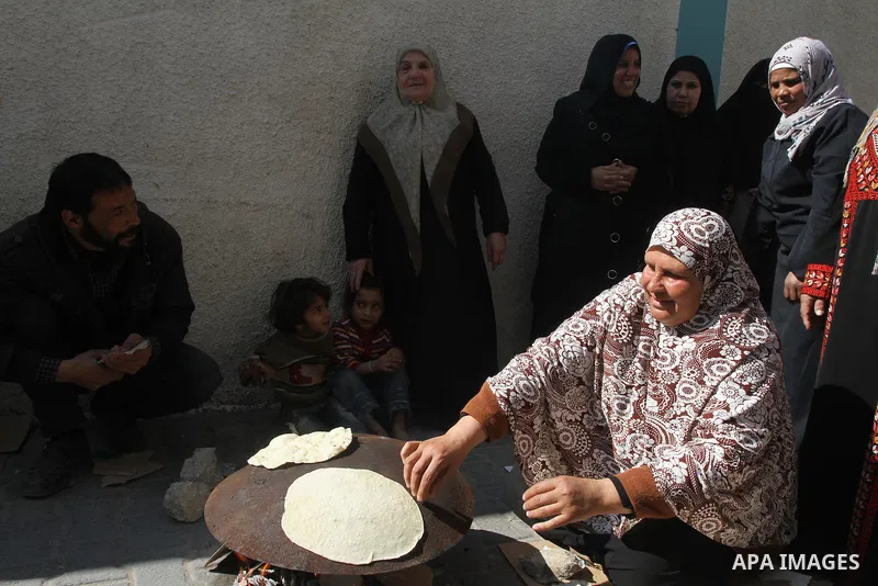 A Palestinian woman bakes bread during a protest against the UNRWA decision to reduce of the food aid in front of the headquarters United Nations Relief and Works Agency (UNRWA), in Gaza city, on Feb. 18, 2014. Photo by...