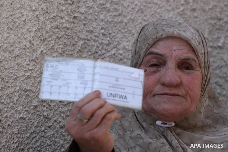 A Palestinian woman holds a UNRWA card during a protest against the UNRWA decision to reduce of the food aid in front of the headquarters United Nations Relief and Works Agency (UNRWA) in Gaza city, on Feb. 18, 2014. Pho...