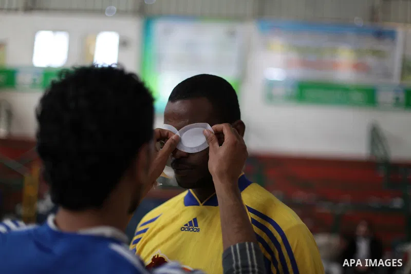 A Palestinian man helps a blind goalball player to get ready to play during a training course, in Gaza city on Feb. 18, 2014. Photo by Ashraf Amra