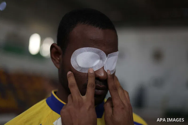 A Palestinian man helps a blind goalball player to get ready to play during a training course, in Gaza city on Feb. 18, 2014. Photo by Ashraf Amra