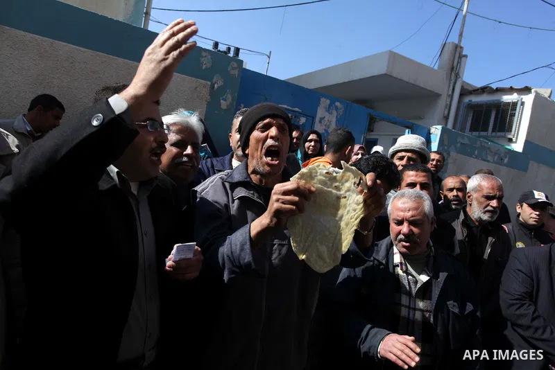 A Palestinian man holds a loaf of bread during a protest against the UNRWA decision to reduce of the food aid in front of the headquarters United Nations Relief and Works Agency (UNRWA), in Gaza city, on Feb. 18, 2014. P...