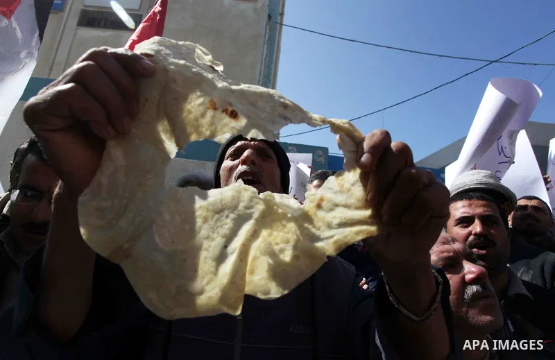A Palestinian man holds a loaf of bread during a protest against the UNRWA decision to reduce of the food aid in front of the headquarters United Nations Relief and Works Agency (UNRWA), in Gaza city, on Feb. 18, 2014. P...