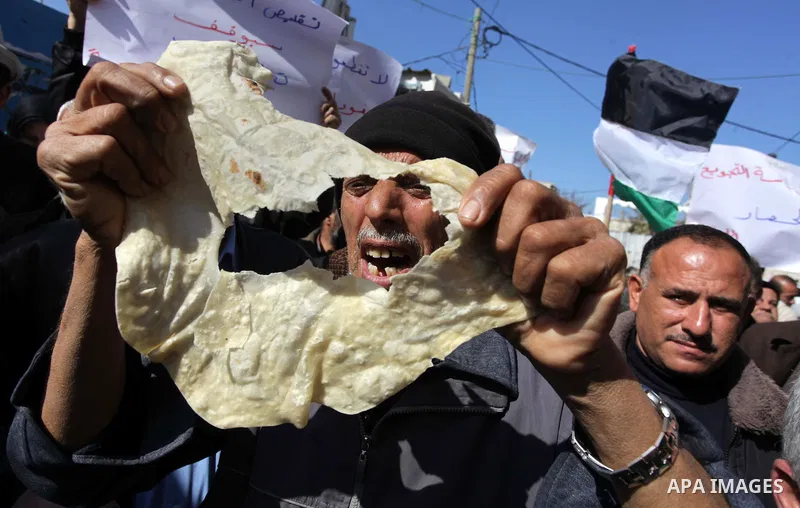 A Palestinian man holds a loaf of bread during a protest against the UNRWA decision to reduce of the food aid in front of the headquarters United Nations Relief and Works Agency (UNRWA), in Gaza city, on Feb. 18, 2014. P...