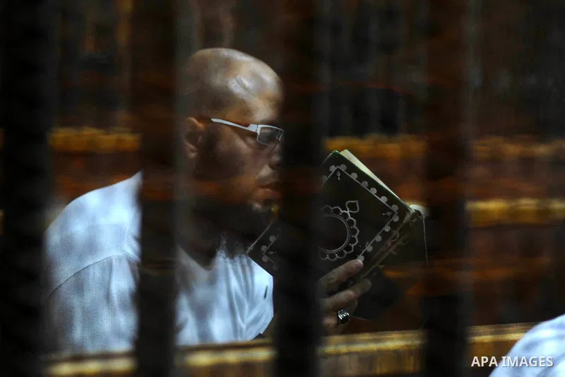 Egyptian suspects in the case of the 'Nasr City terrorist cell' look from inside the defendants cage during their trial, in Cairo on February 18, 2014. Cairo Criminal Court of the Supreme State Security postponed Tuesday...