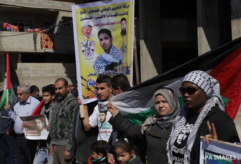 Palestinians hold Palestinian flags and pictures of prisoners during a protest in solidarity with sick prisoners in Israeli jails in Gaza City, on Feb. 19, 2014. Photo by Ashraf Amra