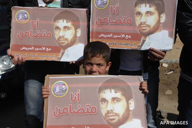 Palestinians hold Palestinian flags and pictures of prisoners during a protest in solidarity with sick prisoners in Israeli jails in Gaza City, on Feb. 19, 2014. Photo by Ashraf Amra