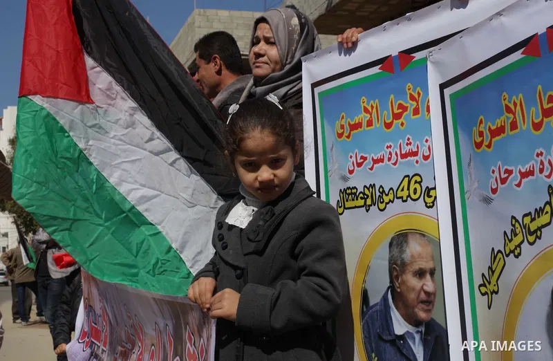Palestinians hold Palestinian flags and pictures of prisoners during a protest in solidarity with sick prisoners in Israeli jails in Gaza City, on Feb. 19, 2014. Photo by Ashraf Amra