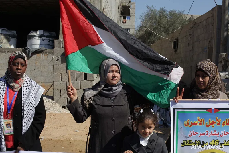 Palestinians hold Palestinian flags and pictures of prisoners during a protest in solidarity with sick prisoners in Israeli jails in Gaza City, on Feb. 19, 2014. Photo by Ashraf Amra