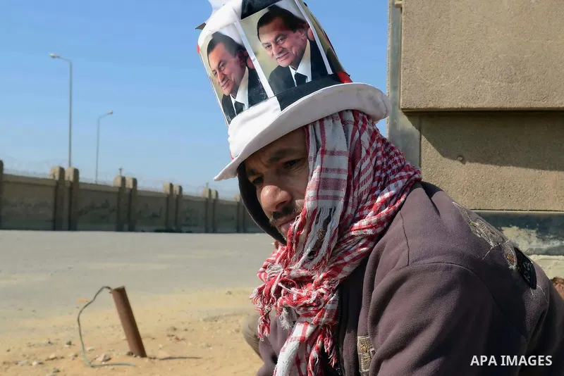 Supporters of former Egyptian president Hosni Mubarak hold his poster outside the police academy in Cairo, Egypt, on Feb. 19, 2014. Photo by Mohammed Bendari
