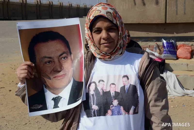 Supporters of former Egyptian president Hosni Mubarak hold his poster outside the police academy in Cairo, Egypt, on Feb. 19, 2014. Photo by Mohammed Bendari