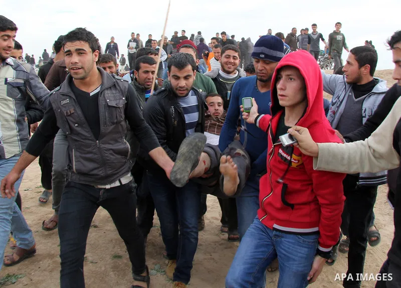 Palestinians carry a fellow protester wounded during clashes with Israeli forces near the border with Israel, east of Jabalia refugee camp in northern Gaza Strip on February 21, 2014. The Israeli army fired live rounds a...