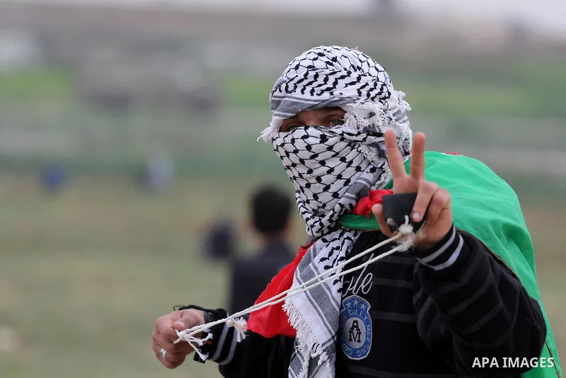 A masked Palestinian protester flashes a victory sign during clashes with Israeli forces near the border with Israel, east of Jabalia refugee camp in northern Gaza Strip on February 21, 2014. The Israeli army fired live...