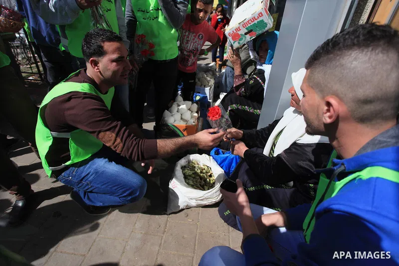Palestinian youth distribute roses during a participate in the campaign " for the good, we gather" honoring for the elderly working women at the streets, in the West Bank city of Ramallah, on Feb. 22, 2014. Photo by Issa...
