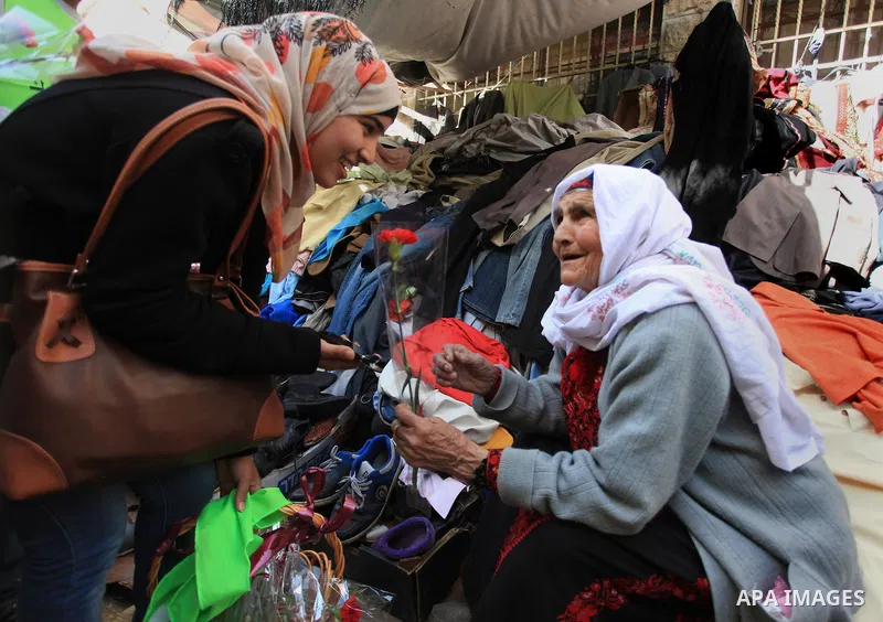 Palestinian youth distribute roses during a participate in the campaign " for the good, we gather" honoring for the elderly working women at the streets, in the West Bank city of Ramallah, on Feb. 22, 2014. Photo by Issa...