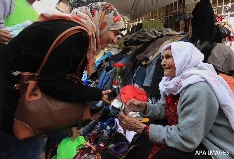Palestinian youth distribute roses during a participate in the campaign " for the good, we gather" honoring for the elderly working women at the streets, in the West Bank city of Ramallah, on Feb. 22, 2014. Photo by Issa...