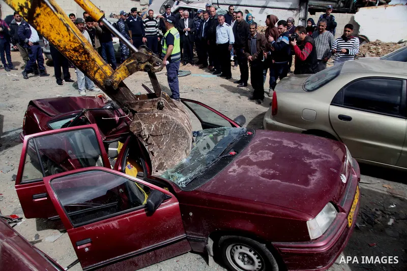 Palestinian police members use a bulldozer to destroy cars during a campaign destroy illegal cars in the West Bank City of Hebron, February 23, 2014. A majority of the so-called "illegal" vehicles are cars bought or stol...