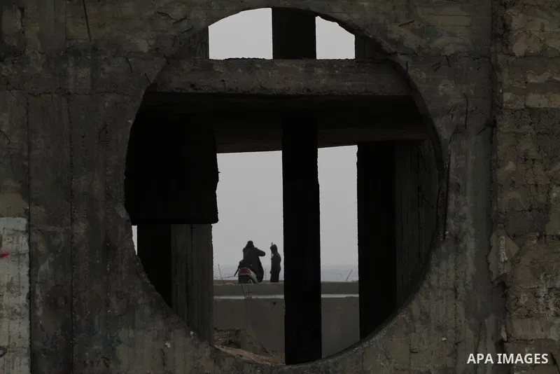 Palestinians walk in a destroyed building at al-Waha area near the Mediterranean Sea beach front, in the northern Gaza Strip, February 23, 2014. The Israeli aircraft and gunboats targeted most of buildings in the area si...