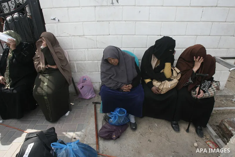 Palestinians wait with their stuff near the gate of the Rafah border crossing on February 23, 2014, while a tent housing a special session attended by Hamas MPs to demand that Egypt lift border crossing restrictions. Egy...