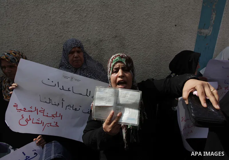 A Palestinian woman holds a UNRWA card during a protest against the UNRWA decision to reduce of the food aid in front of the headquarters United Nations Relief and Works Agency (UNRWA) in Gaza city, on Feb. 25, 2014. Pho...