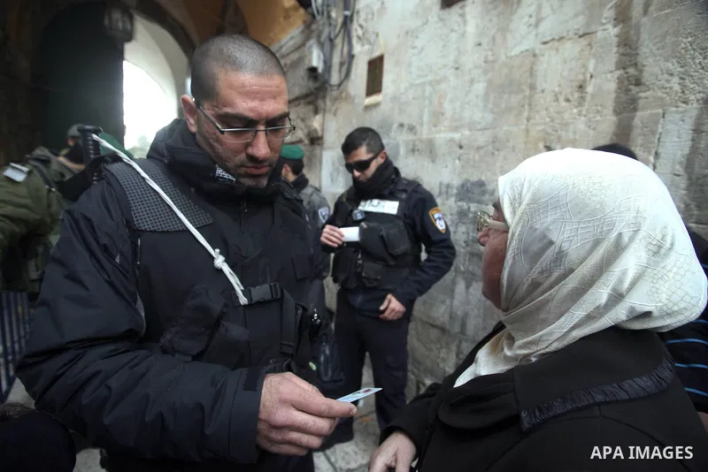 A member of the Israeli security forces checks the ID of a Palestinian woman while he wait to cross an alleyway leading to the al-Aqsa Mosque compound on February 25, 2014 in the Old City of Jerusalem. Israeli police ear...