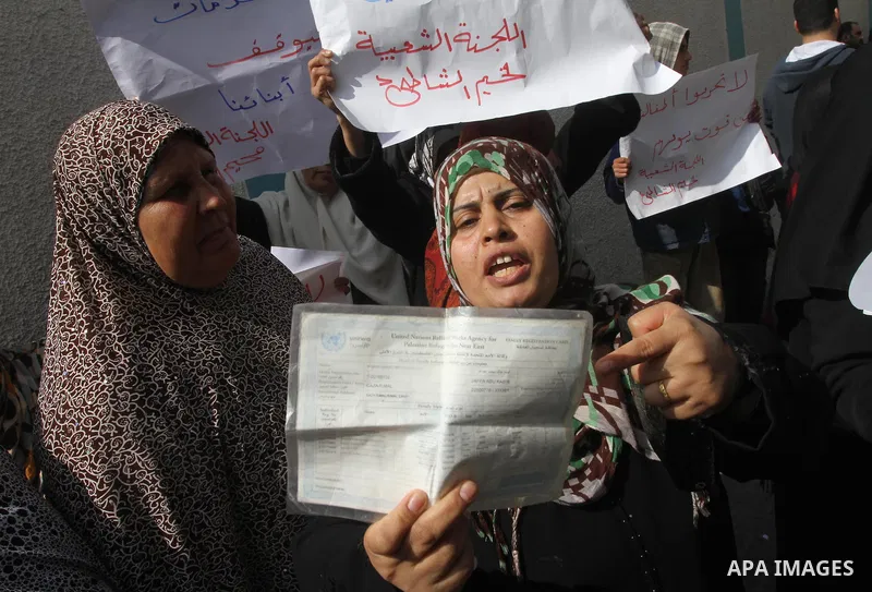 A Palestinian woman holds a UNRWA card during a protest against the UNRWA decision to reduce of the food aid in front of the headquarters United Nations Relief and Works Agency (UNRWA) in Gaza city, on Feb. 25, 2014. Pho...