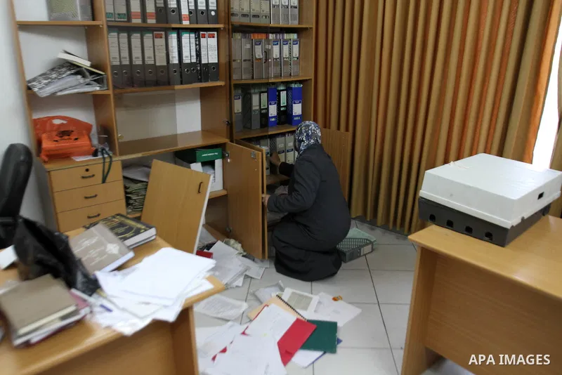 A Palestinian woman inspects damage inside the solidarity foundation for human rights after its stormed by Israeli army, in the West Bank city of Nablus, on Feb. 25, 2014. Photo by Nedal Eshtayah