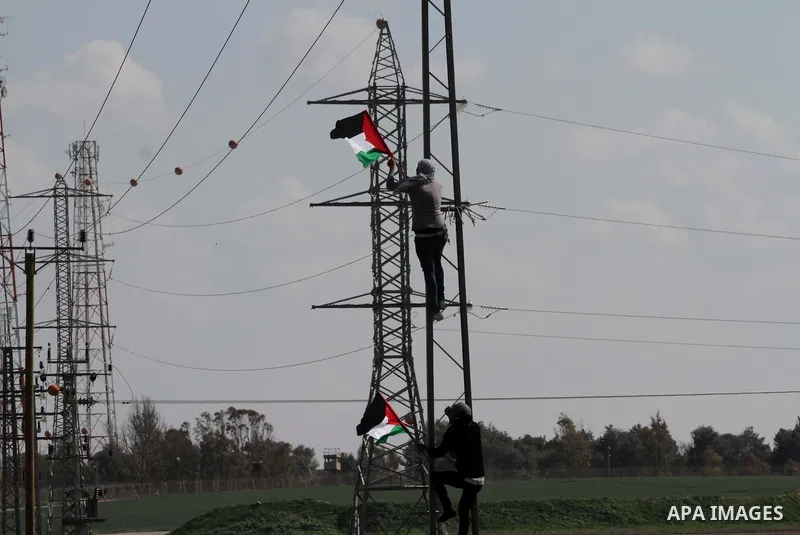 Palestinian protesters put up their national flag during clashes with Israeli security forces near Nahal Oz border crossing with Israel, east of Gaza City, on February 25, 2014 following a demonstration to commemorate th...