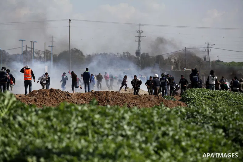 Palestinian protesters run seek for cover from tear gas fired by Israeli security forces during clashes near Nahal Oz border crossing with Israel, east of Gaza City, on February 25, 2014 following a demonstration to comm...