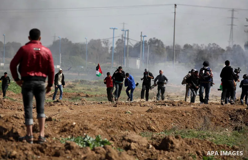 Palestinian protesters run seek for cover from tear gas fired by Israeli security forces during clashes near Nahal Oz border crossing with Israel, east of Gaza City, on February 25, 2014 following a demonstration to comm...