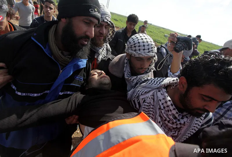 Palestinians carry an injured man during clashes with Israeli security forces near Nahal Oz border crossing with Israel, east of Gaza City, on February 25, 2014 following a demonstration to commemorate the Ibrahimi Mosqu...