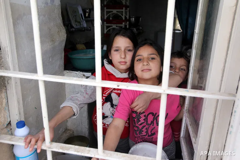 Children of Ahmad Mansour, pose for a picture through a window at their family's house in the village of al-Kitteh western city of Jerash, 50 km northern the Jordanian capital Amman on February 21, 2014 . Mansour, 54, ar...