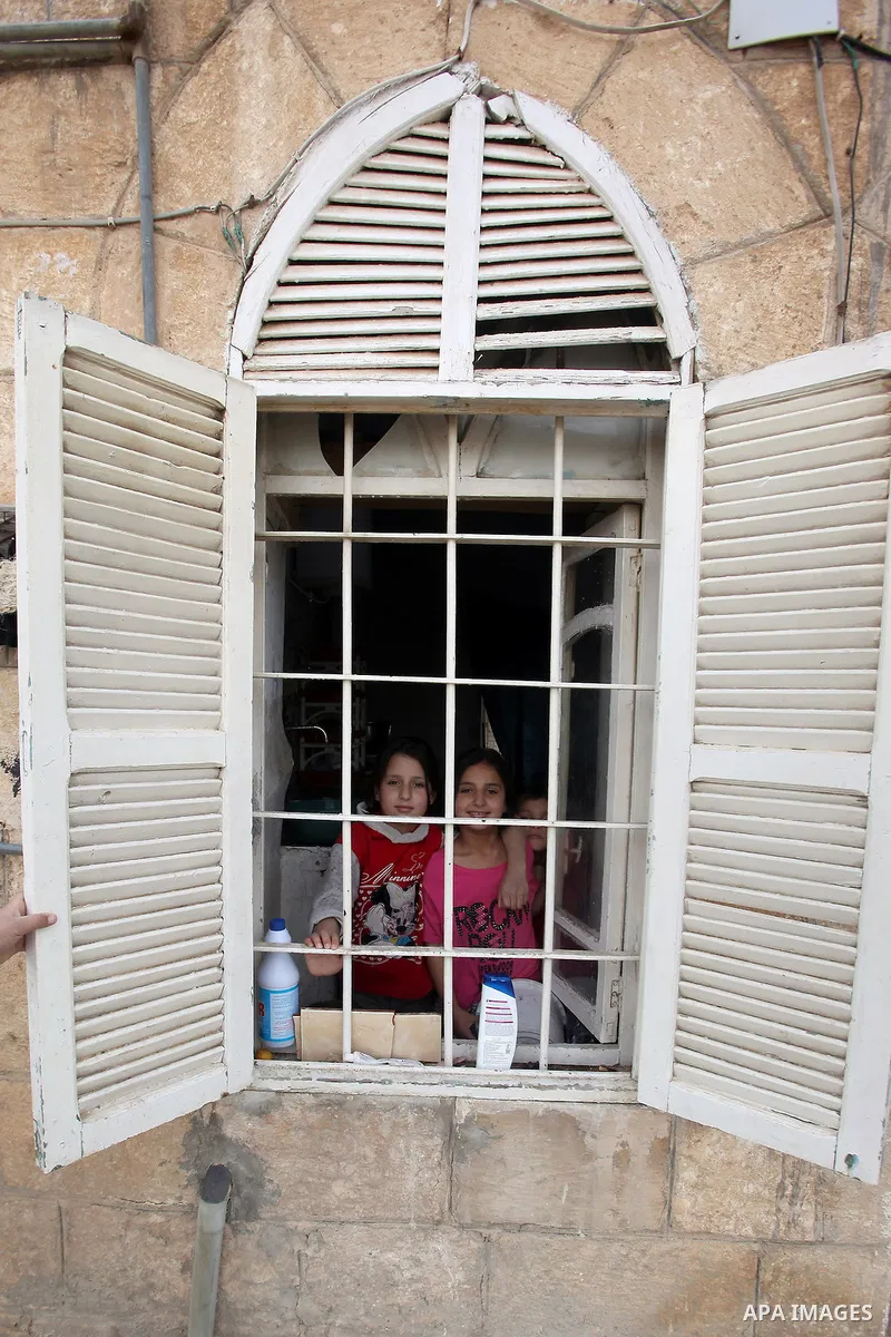 Children of Ahmad Mansour, pose for a picture through a window at their family's house in the village of al-Kitteh western city of Jerash, 50 km northern the Jordanian capital Amman on February 21, 2014 . Mansour, 54, ar...
