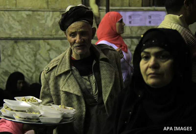 A Egyptian man distributes foods to worshippers after El Ishaa prayers at the Al-Hussein mosque, during celebration day of "Moulid Al-Hussein" the birthday of Prophet Mohammad's grandson Hussein in Cairo, February 25, 20...