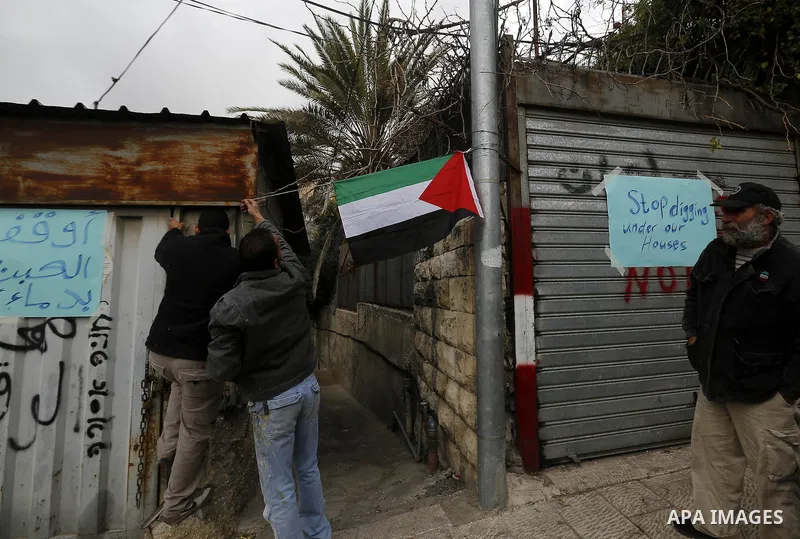 Palestinians hang a placards with writing 'stop digging under our houses' in the Wadi Helweh neighborhood, in Jerusalem, Feb. 26, 2014. A retaining wall, close to houses adjacent to the Moroccan Gate in Jerusalem, collap...