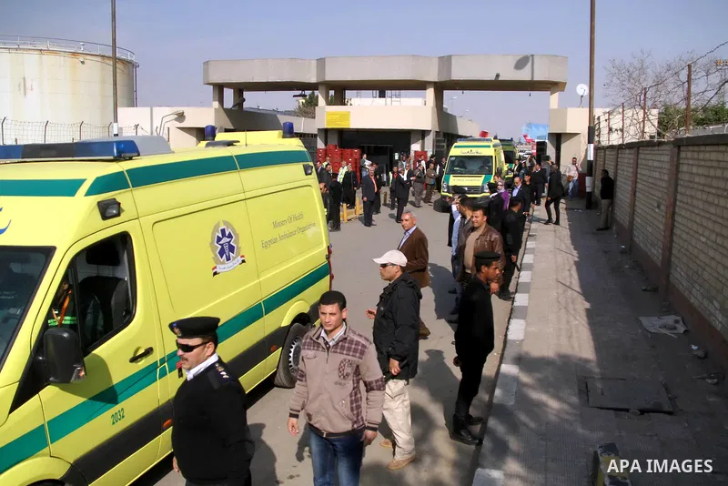 Egyptian security stand guard as ambulances drive out of Cairo international airport on February 26, 2014, carrying the bodies of seven Egyptian victims who were found shot dead in Jalluta, near Benghazi in eastern Libya...