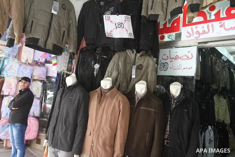 A Palestinian vendor displays his goods at shop in Gaza city, on March 1, 2014. Palestinian vendors campaign discounts on prices of clothes to confront the sharp reduction in demand due to the blockaded territory’s econo...