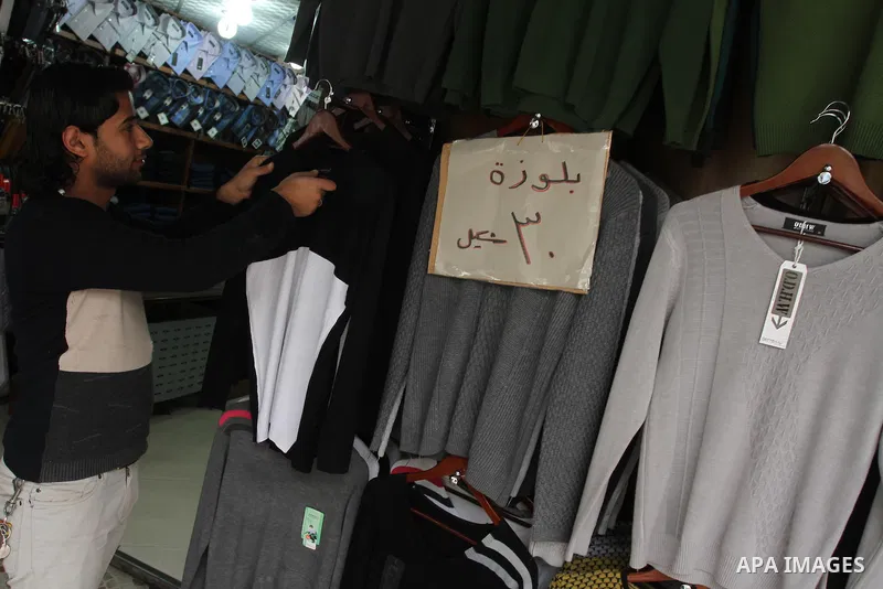 A Palestinian vendor displays his goods at shop in Gaza city, on March 1, 2014. Palestinian vendors campaign discounts on prices of clothes to confront the sharp reduction in demand due to the blockaded territory’s econo...