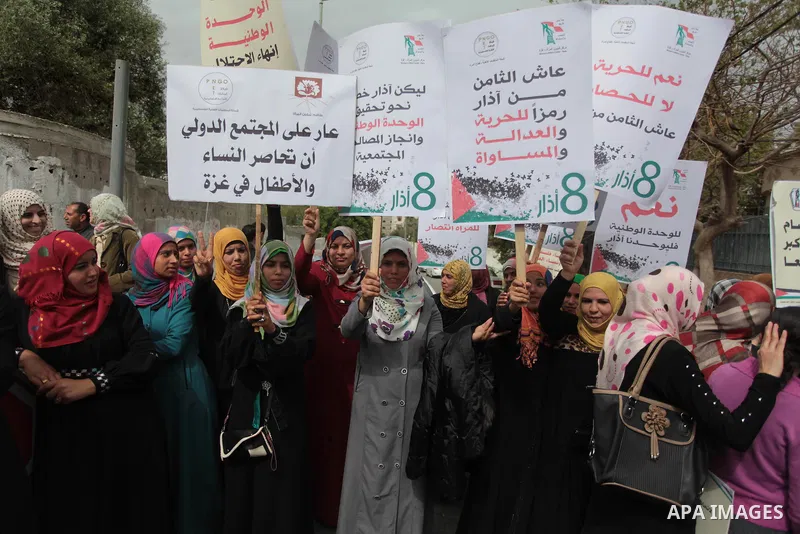 Palestinian women raise placards during a march on the occasion of International Women's Day in Gaza City on March 8, 2014. Photo by Ashraf Amra